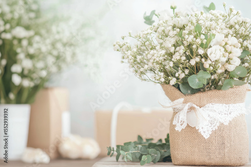 Rustic floral arrangement in burlap vase with eucalyptus and baby's breath on wooden table
