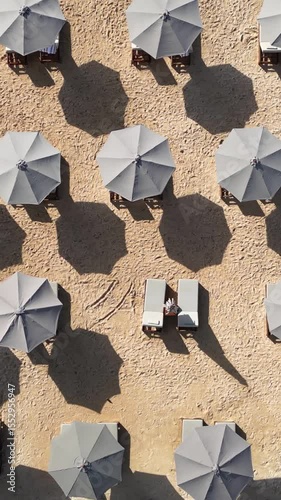 Top-down aerial video of beach umbrellas at white sand beach at sunny day. Nusa Dua. Bali.Indonesia.Vertical video