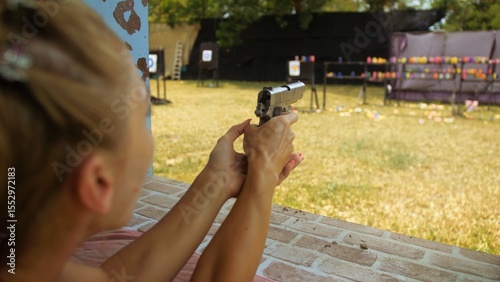 Woman shoots at shooting range with pneumatic gun. Outdoors entertainment for tourists in Thailand.Active leisure on vacation, traveling in Asia.Practice in shooting gallery safe legal pistol weapons