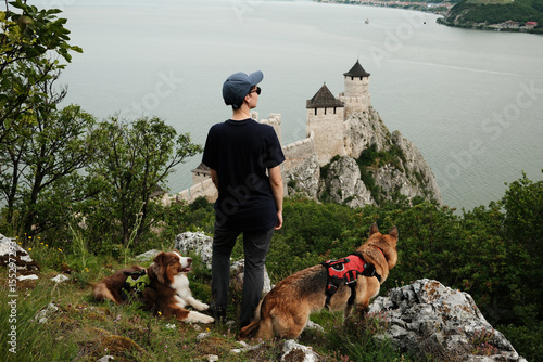 Photography Woman standing with two dogs near Golubac Fortress, overlooking the Danube River in Serbia country