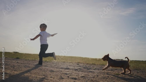 Boy running with dog. Child is running outside with a dog. A young woman is embracing her friend and nature in the sunlight and enjoying the happiness and energy. A child sprinting lifestyle.