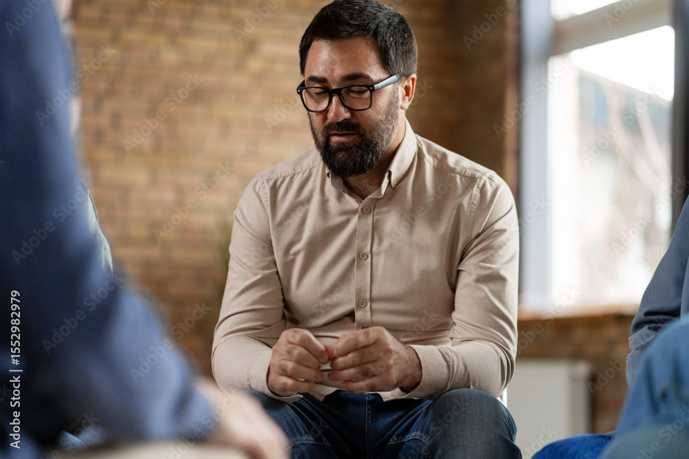 Obraz premium Pensive man listening to colleagues during group therapy session