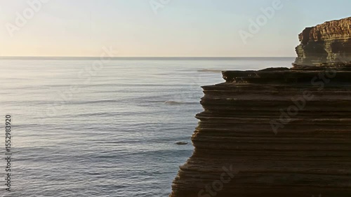 Crisp Morning Light Illuminating Rugged Coastal Cliffs and Serene Ocean Waters with Gentle Waves