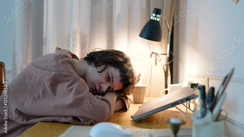 Depressed exhausted woman lying with head on table beside laptop, mental fatigue and disengagement. Work burnout, motivational loss, emotional numbness, task avoid, digital overload, indoor inertia