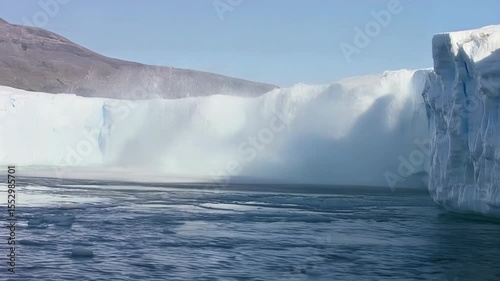 Massive Ice Calving from Glacier into Serene Water under Bright Sunlight in Natural Landscape