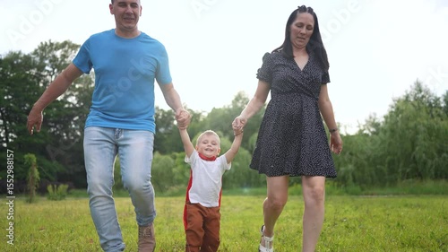 Man and woman running in a field. Parents and children swinging outside. A young girl playing with the grass in nature and nature is playful. A couple is sprinting across a field lifestyle.