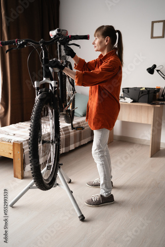 Female cyclist prepares bike for summer season by repairing bicycle at home