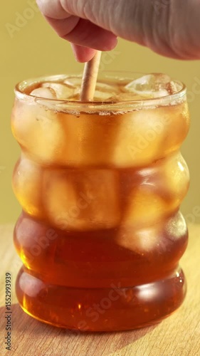 Iced tea is stirred with a paper straw.
