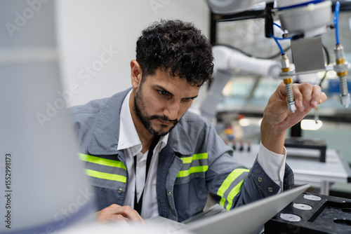 Latino robotic development engineer working robot arm connection control at electronic futuristic science laboratory. Hispanic technician learning innovation machine in automated engineering academy.