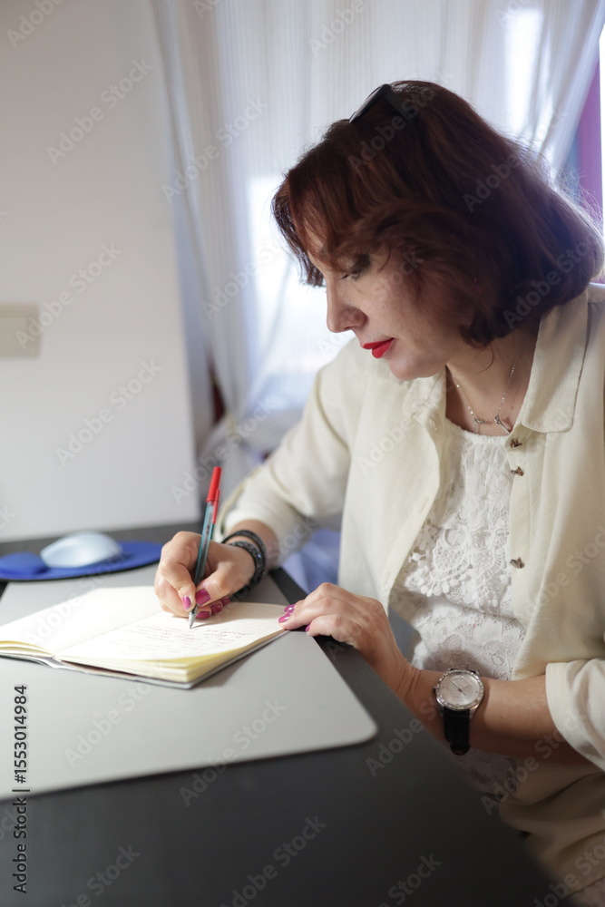 Naklejka premium Businesswoman writing notes in notebook at office desk