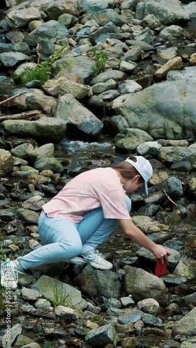 Girl photographing a river in the forest. Mountain river in the Alps.