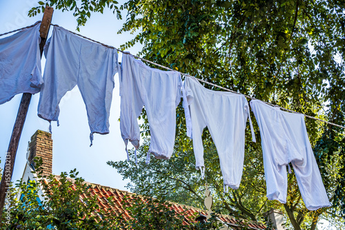 Colorful clothes drying on a line amidst lush green grass in a rural area during bright daytime
