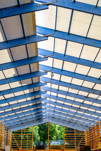 Construction progress of a building with exposed roof structure showcasing modern architectural design under clear blue sky