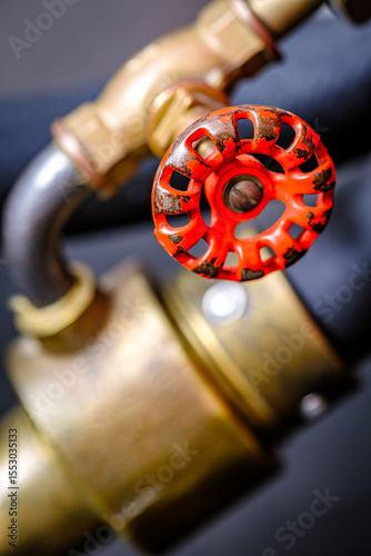 Close-up view of a vintage brass valve against a vibrant red background showcasing intricate design and craftsmanship