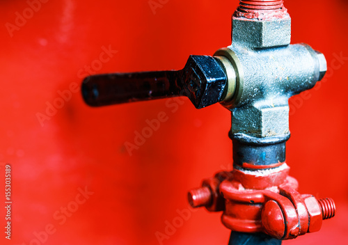 Close-up view of a vintage brass valve against a vibrant red background showcasing intricate design and craftsmanship