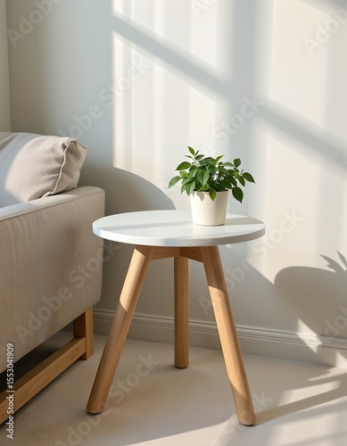 A minimalist cozy corner featuring a small white round table with wooden legs and a green potted plant. Soft natural sunlight casts shadows on the cream wall. Ideal for interior design, lifestyle.