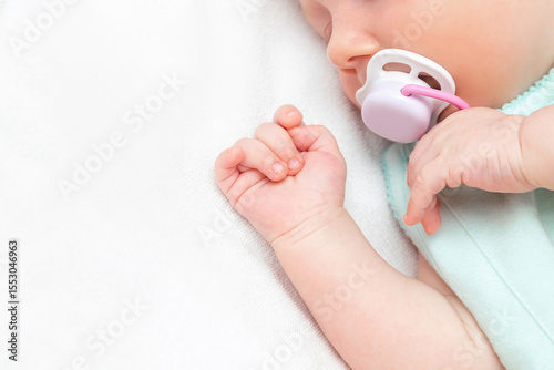 Cute little newborn infant baby with nipple sleeping lying on bed sheet.Close up of child hands with pacifier.happy family day,daycare nursery,motherhood concept.