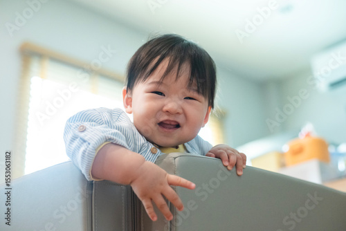 Baby 8 months try to climb escapes from the playpen. The child proud and happy to climbs the playpen successfully.