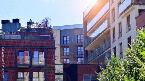 New modern block of flats in green area. complex. New modern block of flats in green area. European residential architecture harmonizing with nature. Eco-friendly living in city with greens.