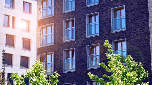 New modern block of flats in green area. complex. New modern block of flats in green area. European residential architecture harmonizing with nature. Eco-friendly living in city with greens.