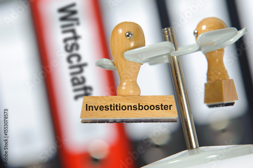 Ein Holzstempel ist beschriftet mit dem Aufdruck Investitionsbooster