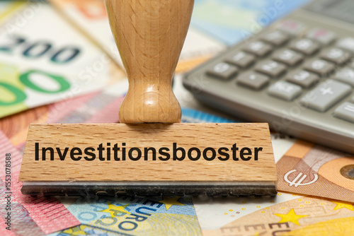 Ein Holzstempel ist beschriftet mit dem Aufdruck Investitionsbooster