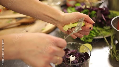Purple basil, lime basil, hands preparing. Close-up captures hands squeezing fresh lime juice over purple basil into food processor while making pesto, using vibrant, fresh herbs and vegetables