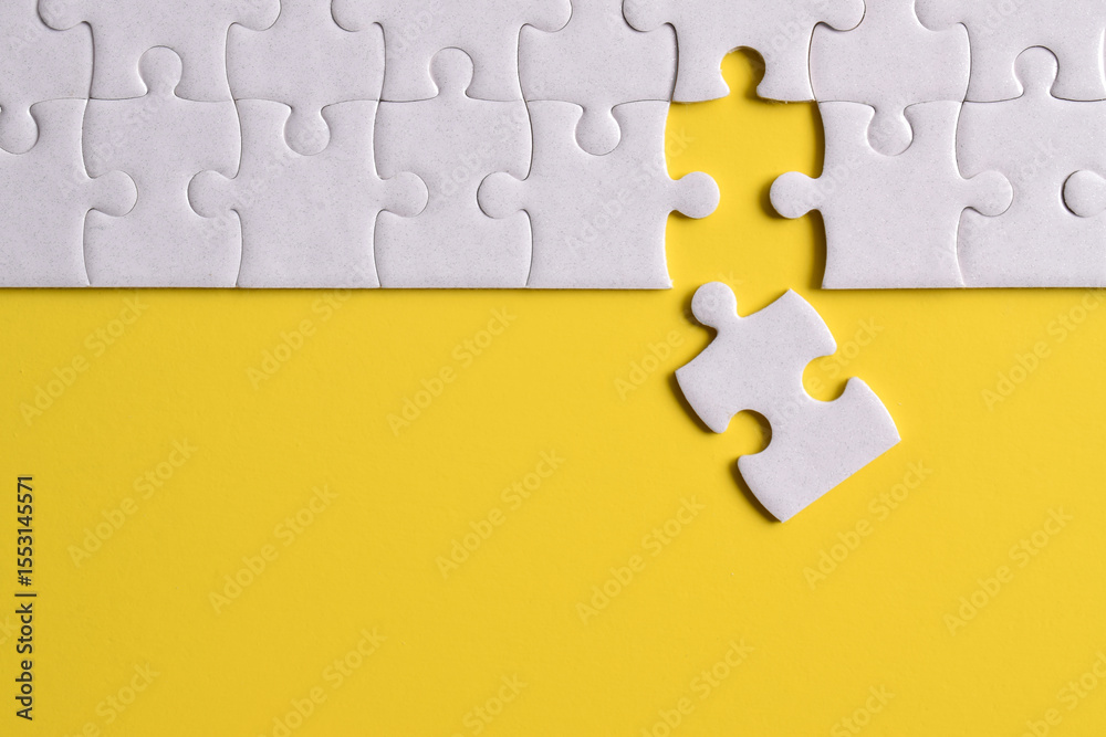 Fototapeta premium White puzzle pieces on yellow background. Flat lay. Top view