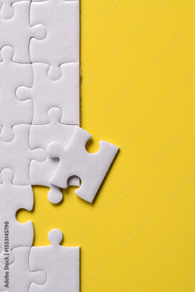 Obraz premium White puzzle pieces on yellow background. Flat lay. Top view