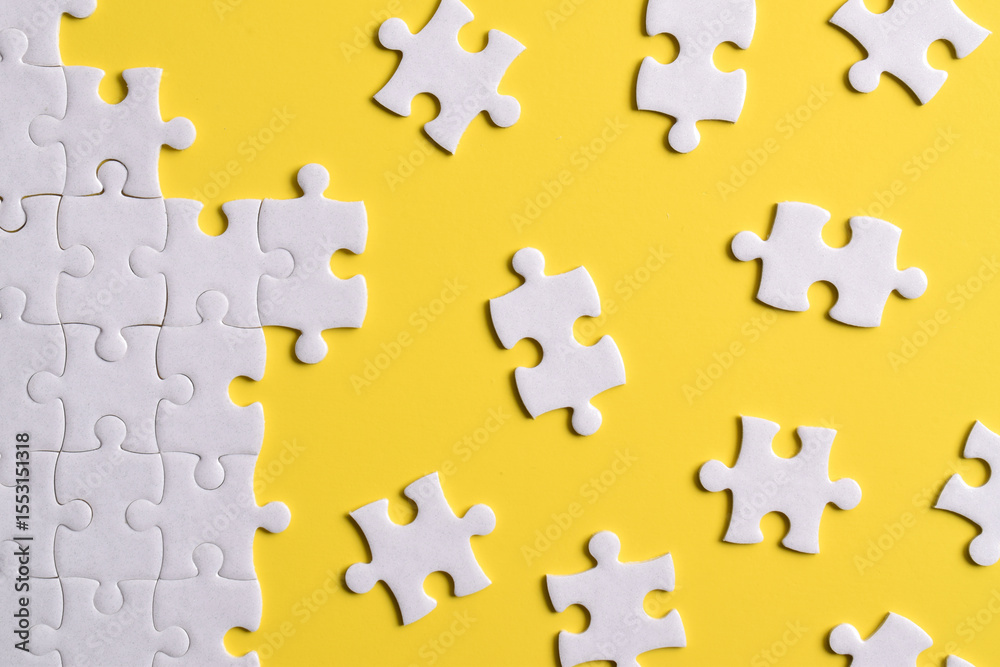 Naklejka premium White puzzle pieces on yellow background. Flat lay. Top view