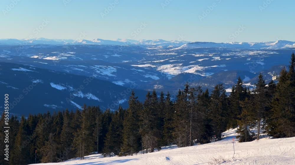 Hafjell Alpine Resort skiing down icy ice snow groomed trail run Norway Norge winter ski skier groomed snowboard Øyer mountains Lillehammer early morning blue sky Sjusjoen mountain valley pan left