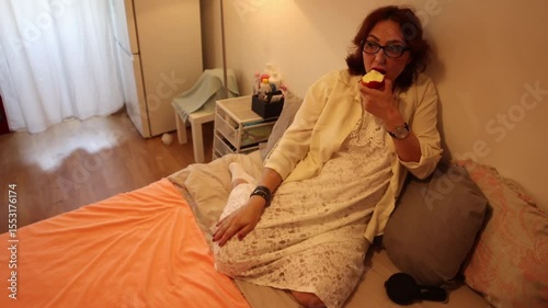 Pregnant woman eating apple and talking on bed