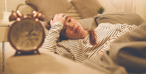Obraz na plátně A tired woman wakes early with a headache, struggling with insomnia and fatigue