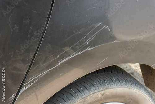 Black car with visible scratches on the rear panel above the wheel