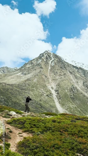 4K Vertical shot of young Indian woman trekking in Himalaya mountains in Miyar Valley, Himachal Pradesh, India. Female explorer exploring hidden mountain treks. Travel background. Backpacking trip.