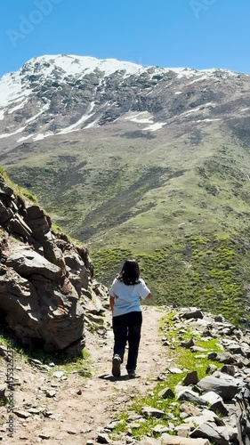 4K Vertical video of young Indian woman hiking in mountains at Hudan Bhatori, Pangi Valley, India. Hiker hiking in mountains during summer season. People trekking, adventure and travel concept.