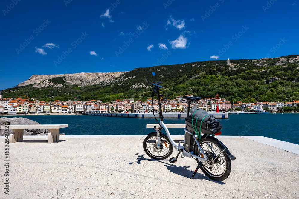 Fototapeta premium Cycling tour on the island of Baska, electric bike parked on a concrete platform by the beach in Baska
