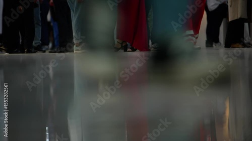 Crowd  walking indoors. Persons legs walking in corridor, low section. Unrecognizable  people in office lobby. Legs and feet of people walking.