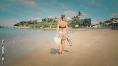 Summer trip to ocean, woman in traditional Asian hat walking on beach alone. Beautiful lady admiring fascinating landscape, traveling to central Asia region, slow motion, cinematic shot on coastline