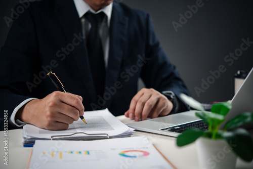 Slika na platnu Hands holding pen signing paperwork on desk with laptop, representing contract signing, important decision-making, and corporate governance in a professional office