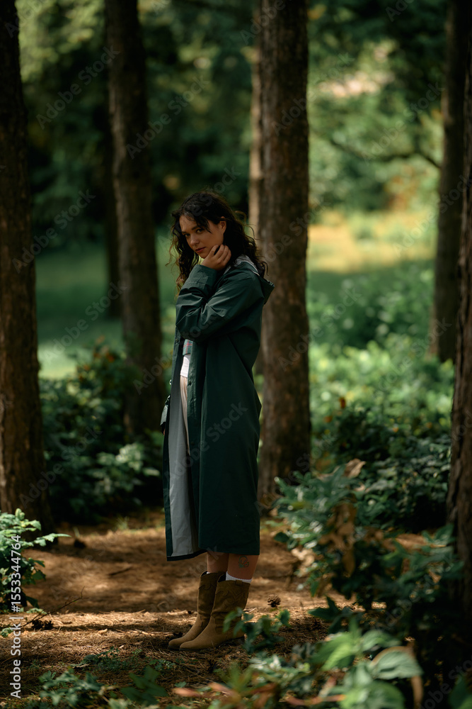 Stylish young woman embraces nature in a green forest wearing a trendy raincoat Stylish young woman embraces nature in a green forest wearing a trendy raincoat