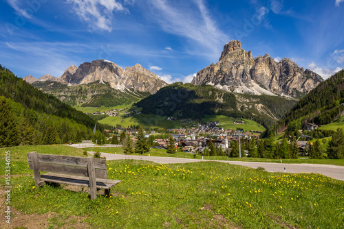 The town of Corvara in the Italian Dolomites in a valley under mountain peaks illuminated by the sun