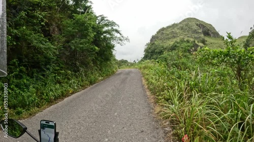 Motorbike journey through narrow tropical road surrounded by hills and greenery in Cebu