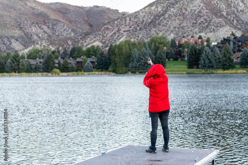 Nottingham lake park dock in Avon, Colorado cold morning with woman on fishing pier casting rod at sunrise in small mountain village ski town city