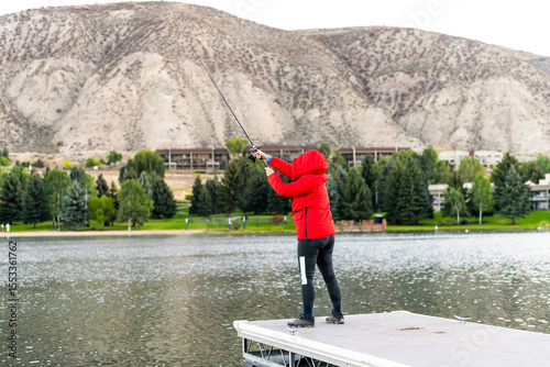 Nottingham lake park dock in Avon, Colorado cold morning with woman on fishing pier casting line at sunrise in small mountain village ski town city