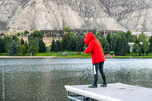 Nottingham lake park dock in Avon, Colorado cold morning with woman in winter coat on fishing pier sunrise in small mountain village ski town city