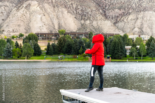 Nottingham lake park in Avon, Colorado cold morning with unrecognizable woman in red winter coat on fishing pier sunrise in small cold mountain town