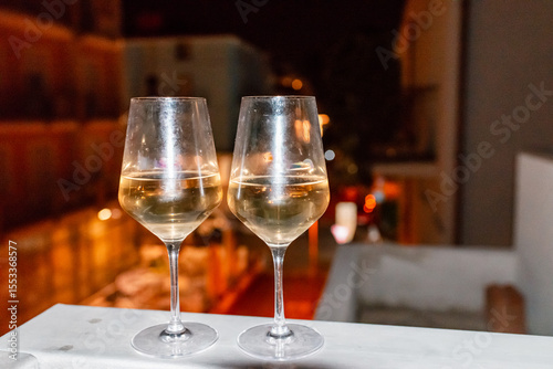 Two glasses of wine on the balcony ledge of a hotel in the summer evening, at night. Vacation time.