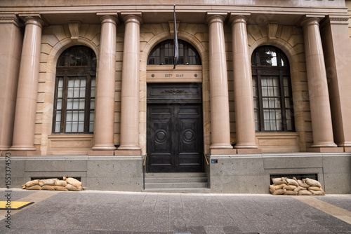 Sandbags along the footpath lining the lower windows of a building in Brisbane CBD before a cyclone