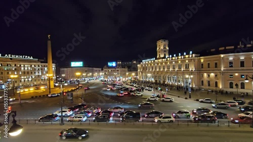 SAINT-PETERSBURG - MAR 31, 2024: Busy city street with a large building in the background. There are many cars on the street, including a few parked in a lot around train station in Saint-Petersburg